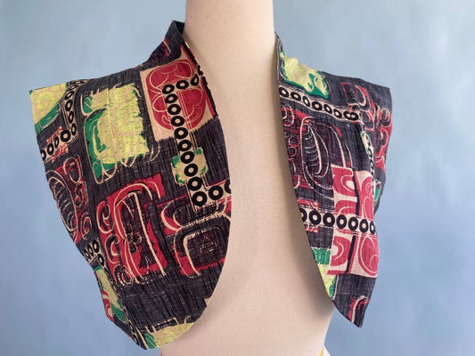 Vintage-inspired cropped jacket with bold abstract print in red, green, and black on mannequin
